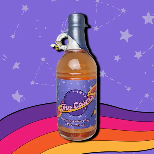 A 500ml bottle of The Cosmo Mead. A wax dipped bottle with a label. A small bee charm hangs from the finger handle on the bottle.