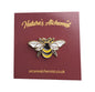 A bee pin badge on a backing card.